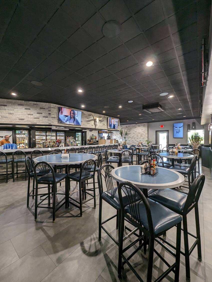 Multiple flat screen televisions mounted above the bar in a restaurant dining room