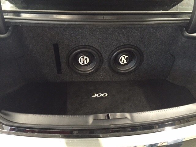 Dual subwoofer enclosure installed in a sedan trunk with a clean carpeted finish